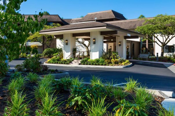 daytime exterior view of madison house senior living in kirkland with well kept landscaping surrounding the parking lot